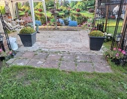 Poster de jardin Un jardin verdoyant avec des fleurs éclatantes et des arbres entourant un étang paisible